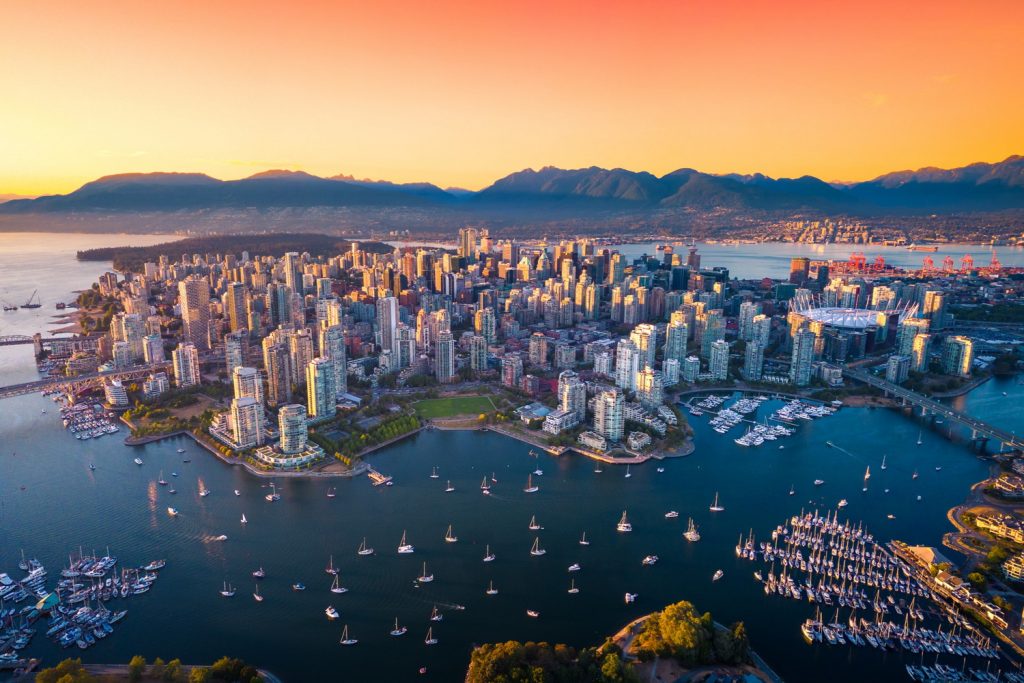 Aerial view of Vancouver at sunset, showcasing the city's skyline, marina, and surrounding mountains, illustrating a vibrant location to find a dentist near you.