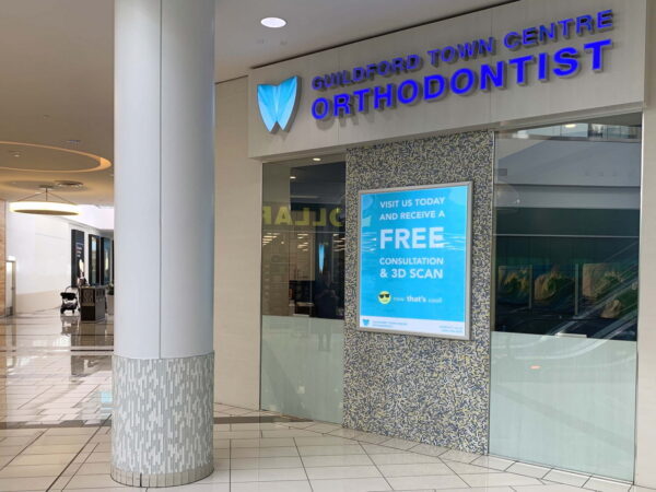 A storefront for an orthodontist located in a shopping center. The sign prominently displays "Orthodontist" and a blue advertisement offering a free consultation and 3D scan. The entrance features large windows and modern decor.