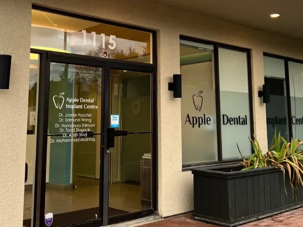 Entrance to Apple Dental, a local dentist near you, featuring large windows with the clinic's name and a planter beside the door.