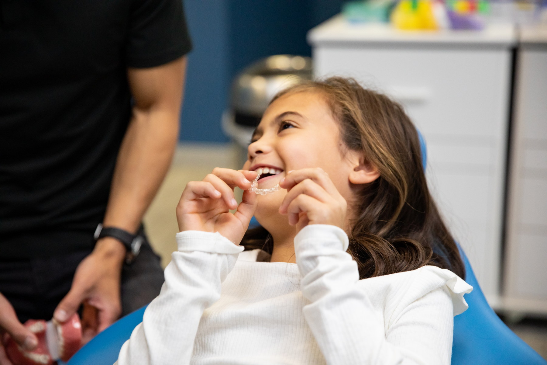Child inserting clear aligner tray with one of our dental professionals at our dental clinic