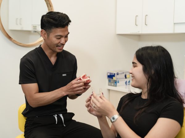 One of our dental professionals showing a teeth model to a patient at our clinic