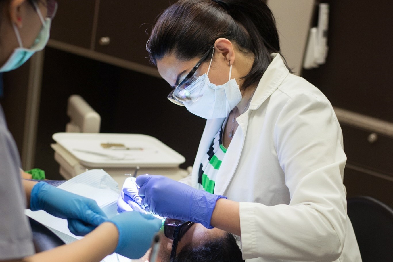 One of our dental professionals examining a patient's teeth with LED light during checkup