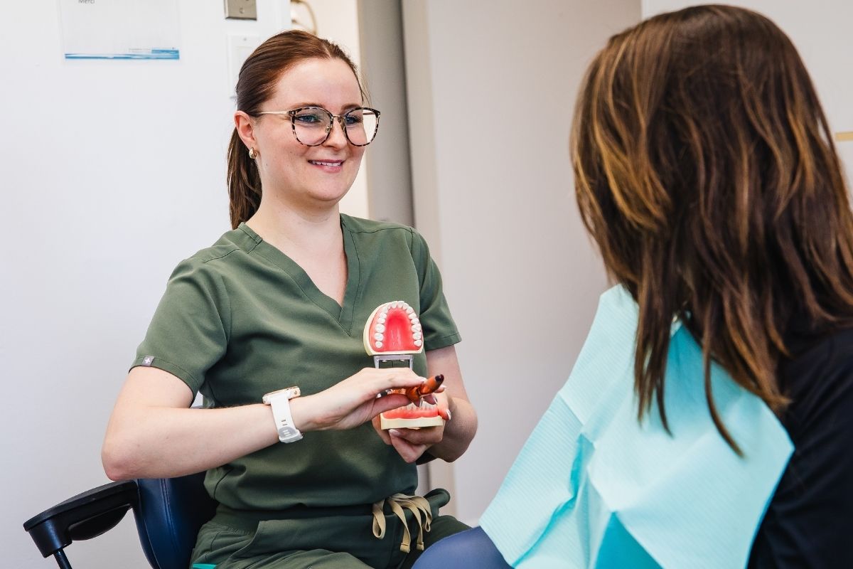 Dental professional demonstrating teeth model to patient at our dental clinic